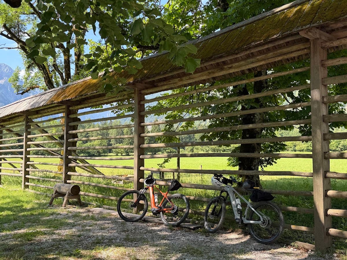 Two bicycles parked beside a traditional wooden hayrack in a grassy field