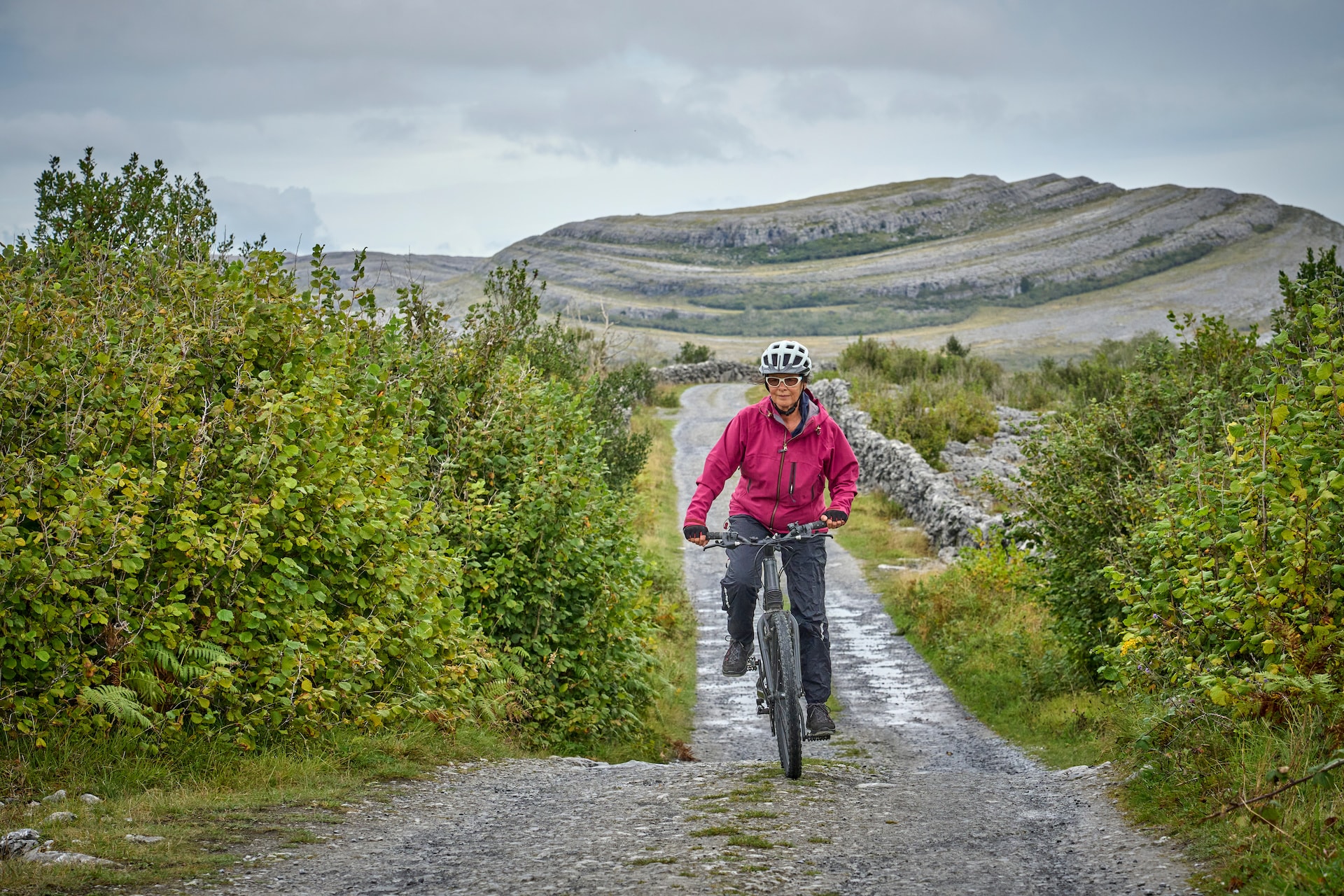 Woman cycling on gravel road near rocky hills outside Ballyvaughan.