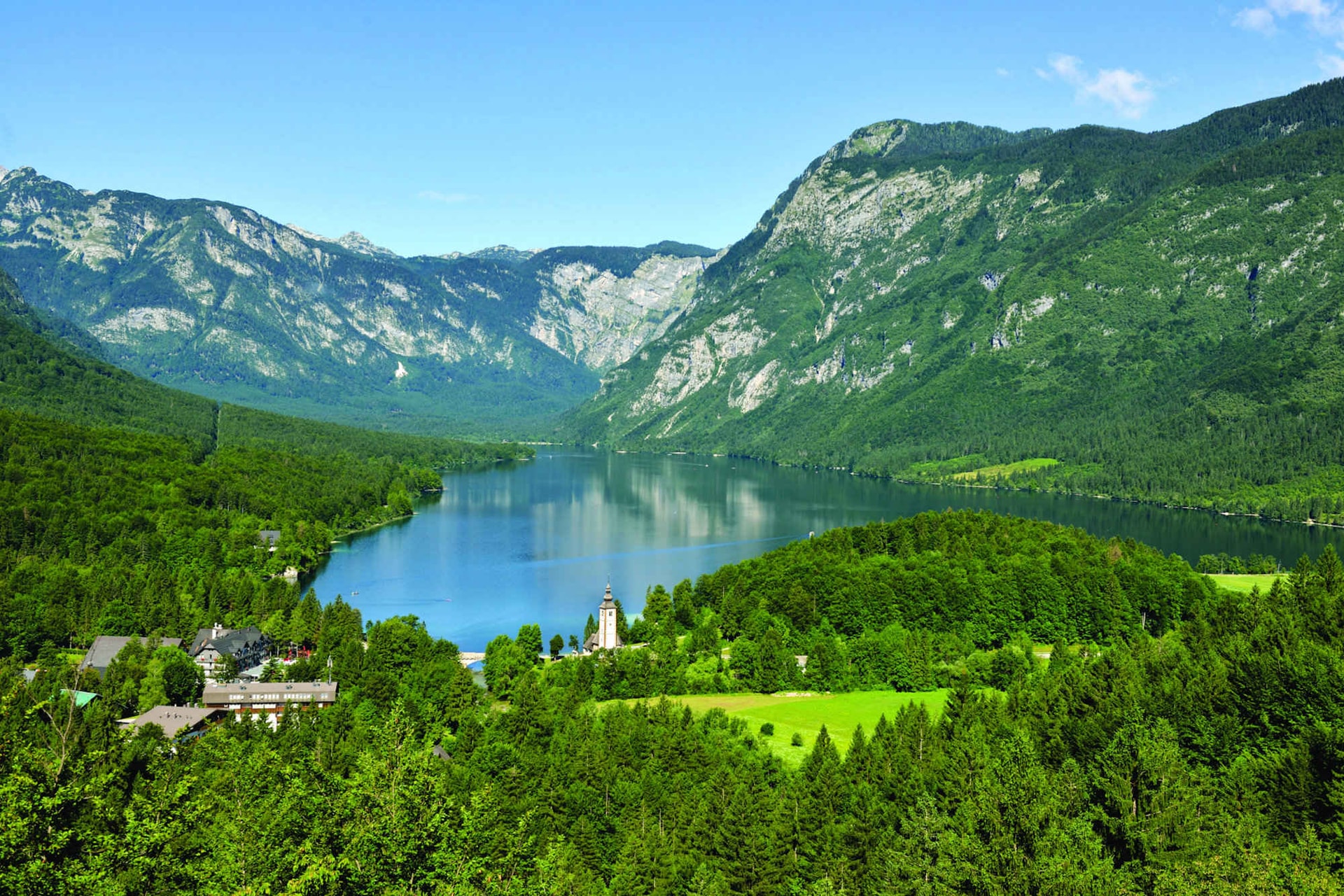 Lake Bohinj with church and surrounding mountains in Slovenia.