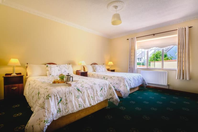 Twin bedroom with yellow walls, floral bedding, and view of suburban houses outside window