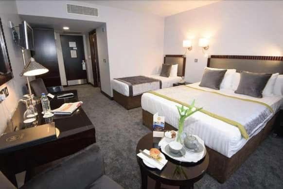 Hotel room with two beds, dark wood furniture, and a small table set for tea.