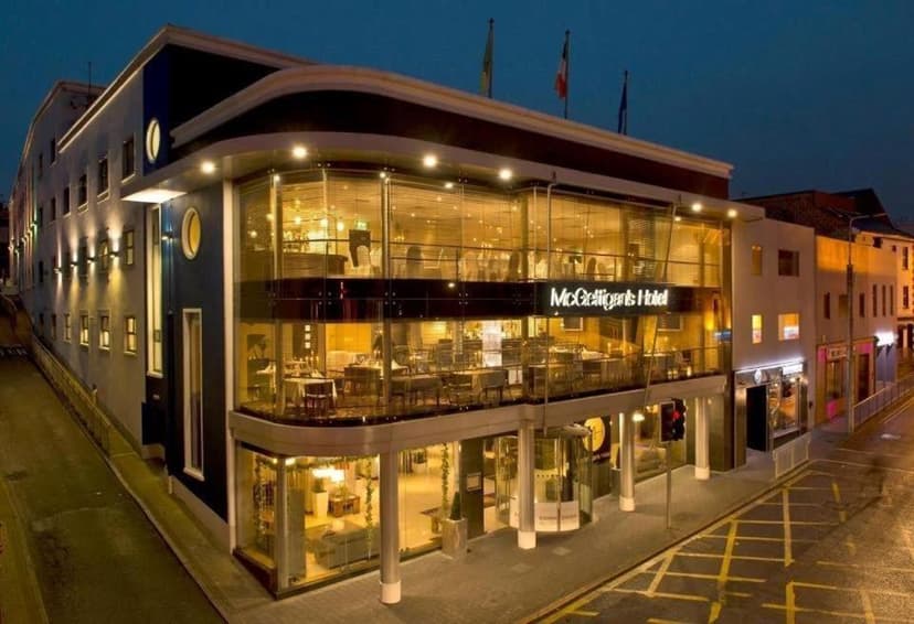 McGettigan's Hotel illuminated at night with glass facade and dining areas visible from street.