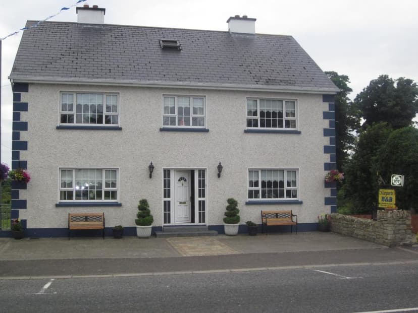 Marguerite's B&B building with white stucco and dark slate roof, viewed from the road.