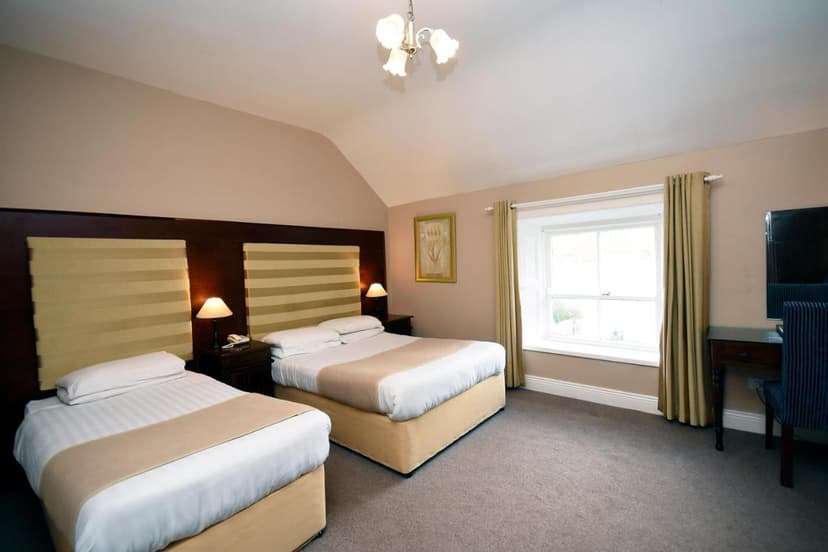 Twin hotel room with beige walls, two beds, and a window with curtains, Leenane.