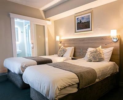 Twin beds in a modern Tralee townhouse room with sliding door to bathroom.