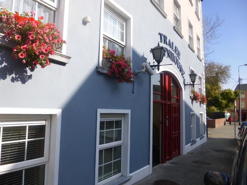 Blue townhouse exterior in Tralee with white trim, red door, and pink flowers in window boxes.