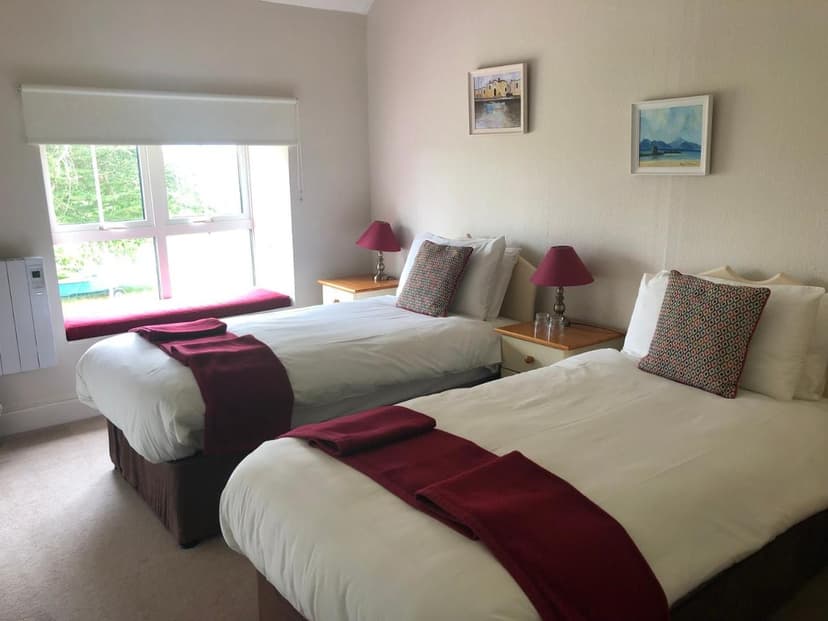 Twin bedroom in Gortamullen House with white bedding, red accents, and artwork above beds.