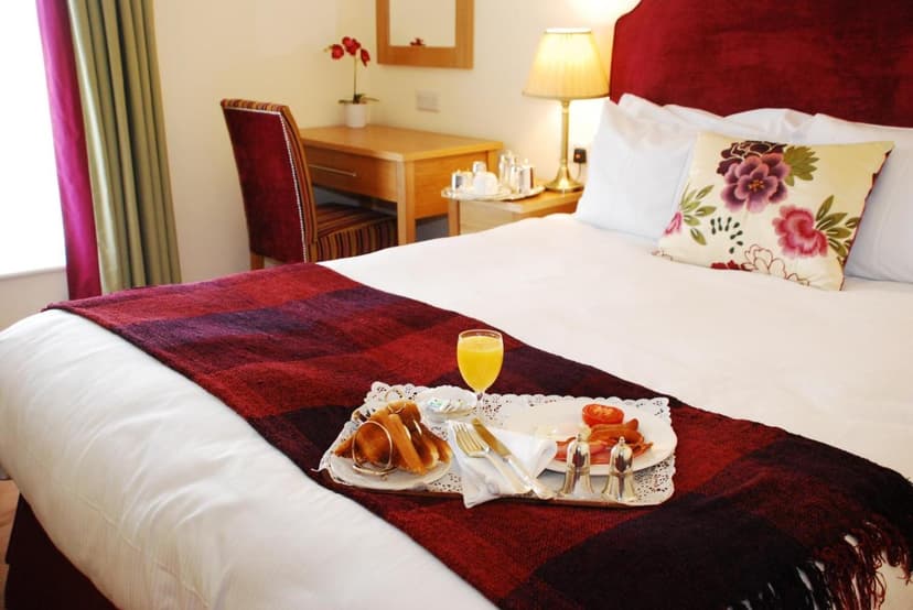 Room service breakfast tray with toast, eggs, and bacon on a bed in Casey's Hotel room.