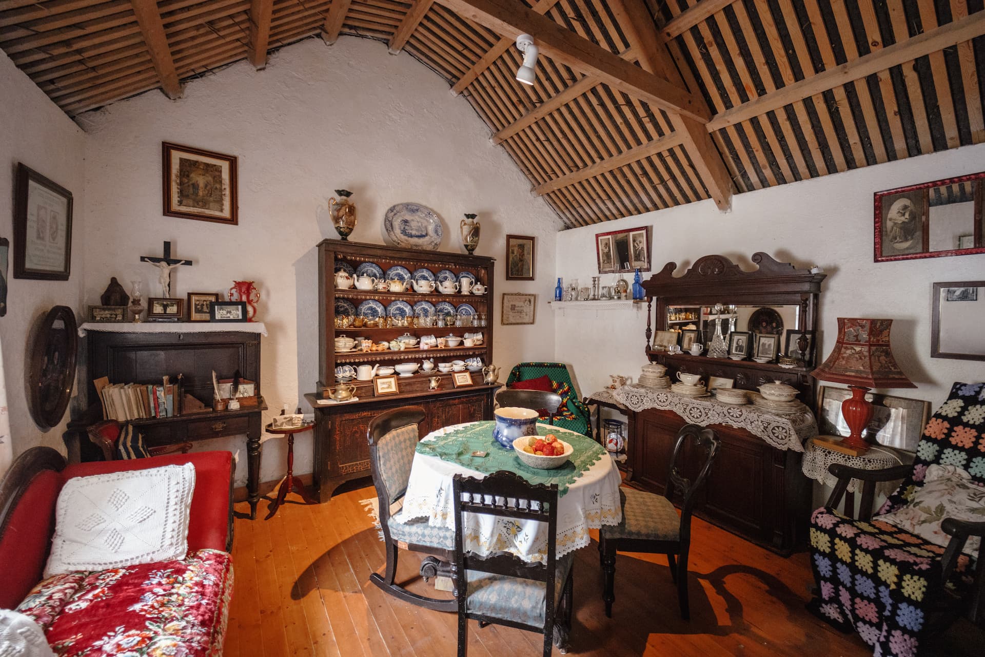 Interior of Glencolmcille Folk Village with antique furniture, china cabinet, and dining table.