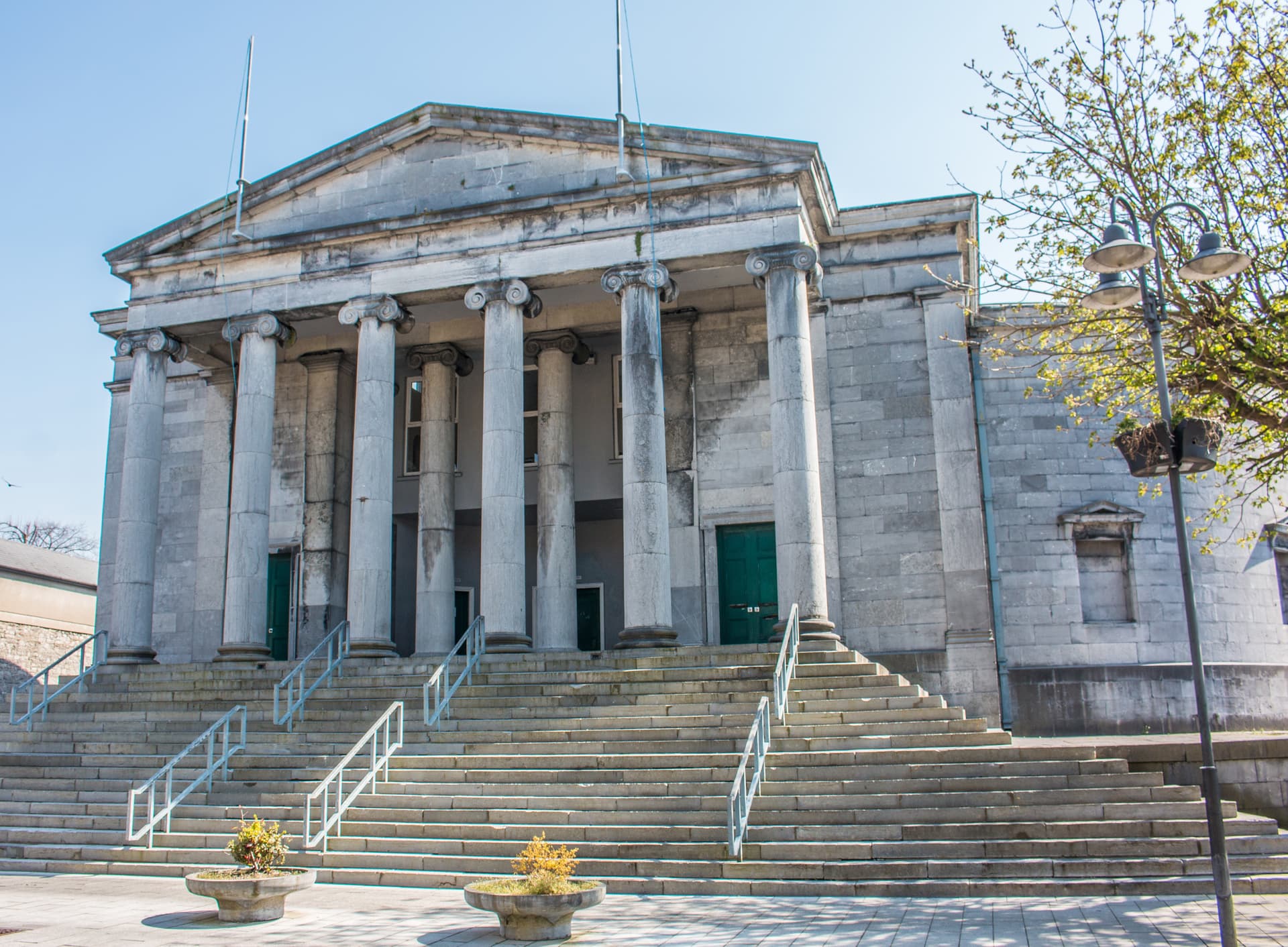 Tralee Courthouse with classical columns and wide stone steps under a clear blue sky.