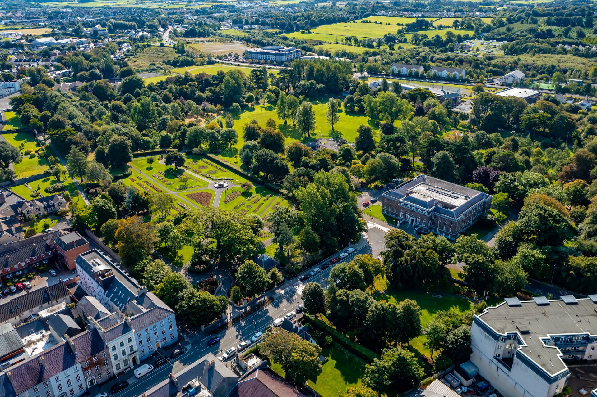 Aerial view of Tralee town center showing extensive green parkland, formal gardens, and surrounding buildings.