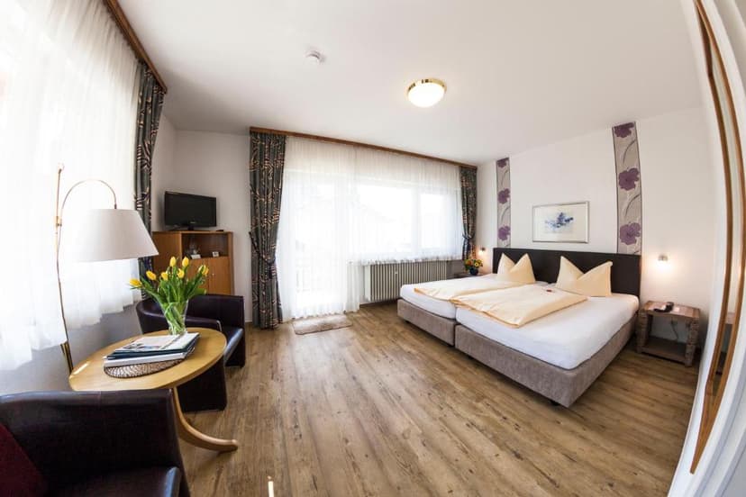 Hotel room in Badenweiler with twin beds, wood floor, and yellow tulips.