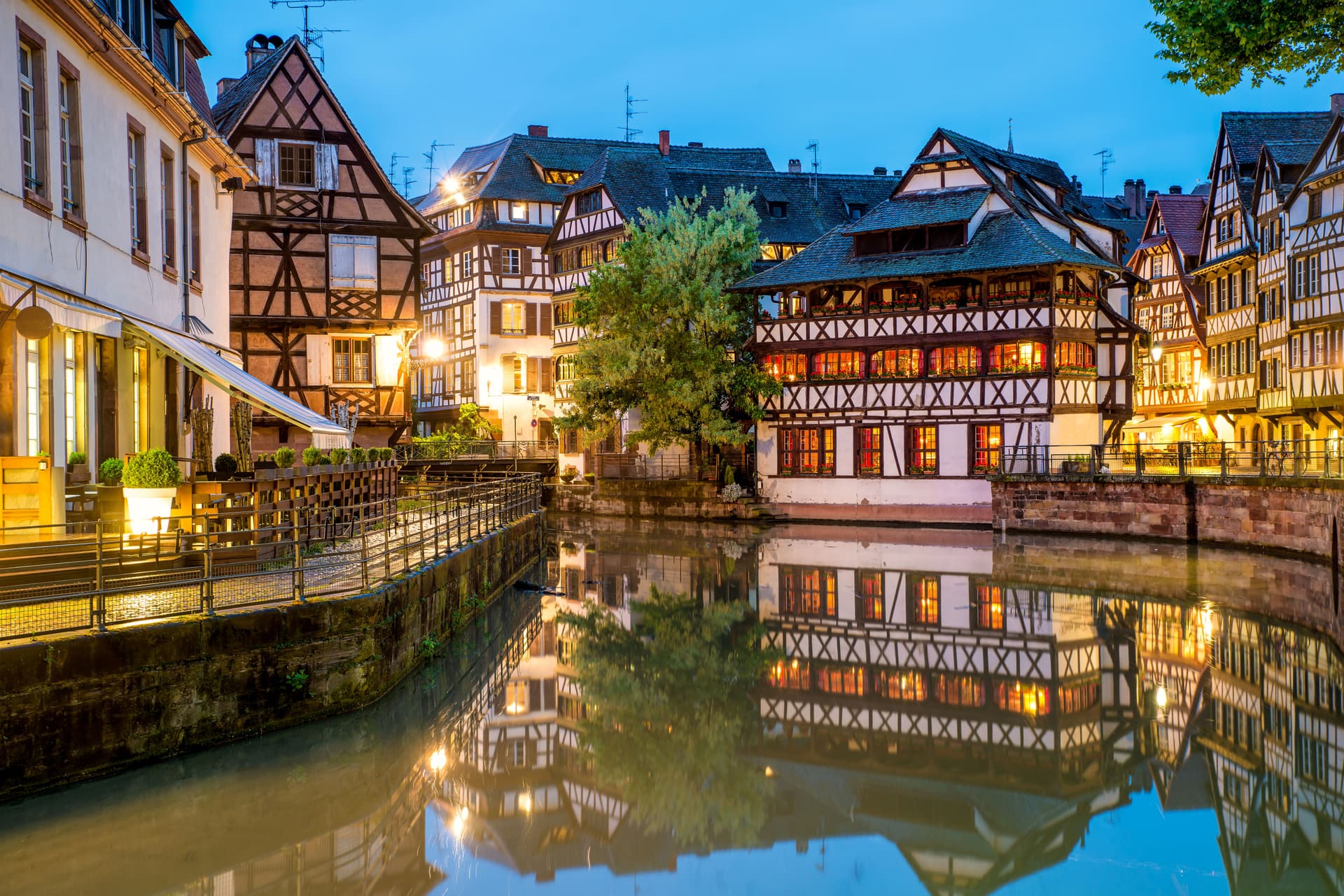 Half-timbered buildings illuminated at dusk reflected in the canal in Strasbourg center.
