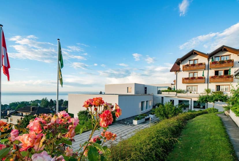 Hotel Rebstock with Swiss flag overlooking a large lake under a blue sky.