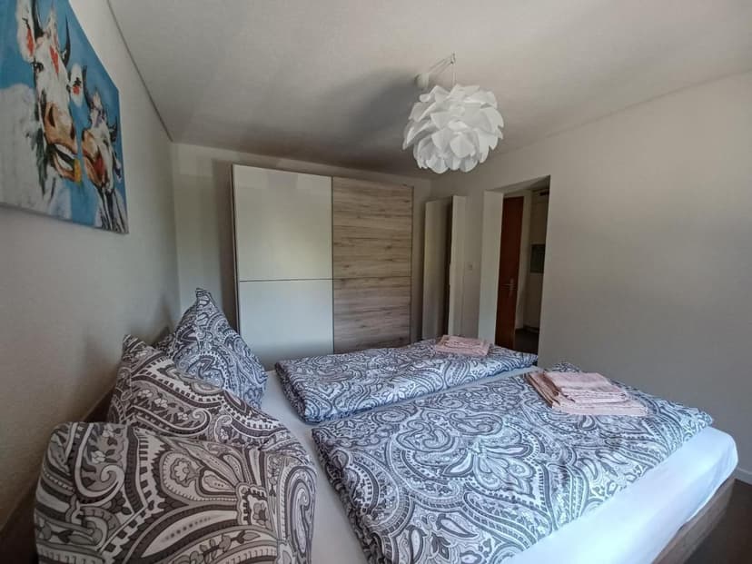 Bedroom with twin beds, paisley bedding, modern wardrobe, and cow art print.
