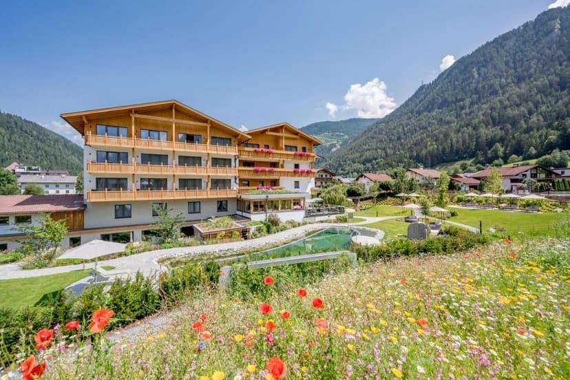 Alpine hotel with wooden balconies, pool, and wildflower meadow in Prutz, Austria