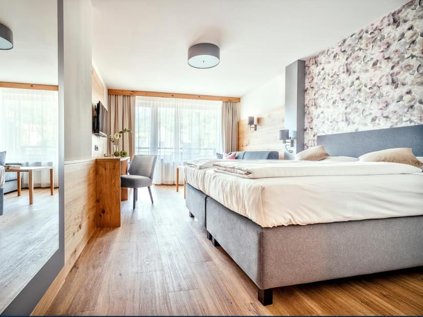 Hotel room at Stadthotel Eggerbräu Imst with wood floors and floral accent wall