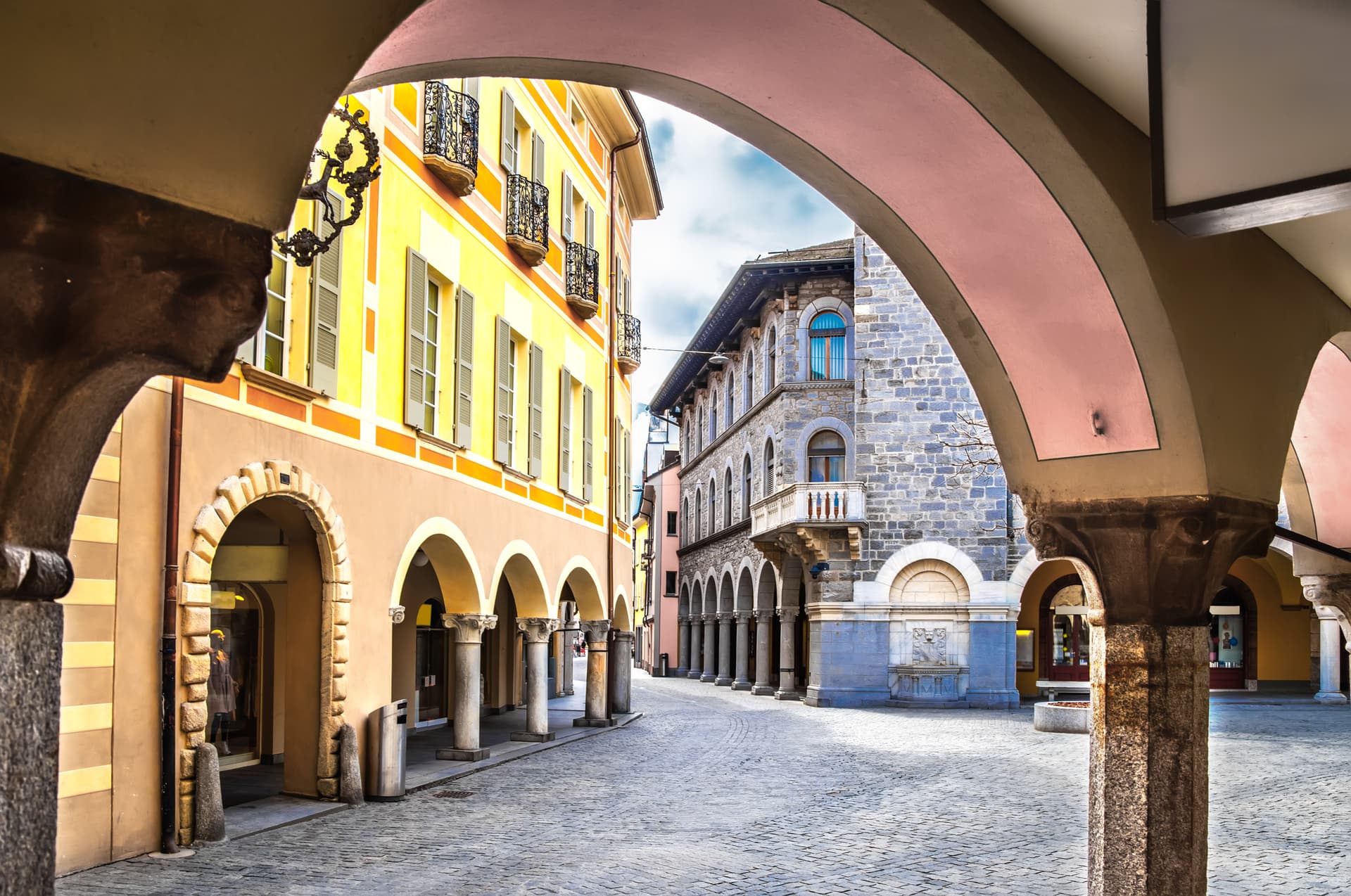 Courtyard arcades of Palazzo Civico in Bellinzona, Switzerland, with cobblestone pavement.