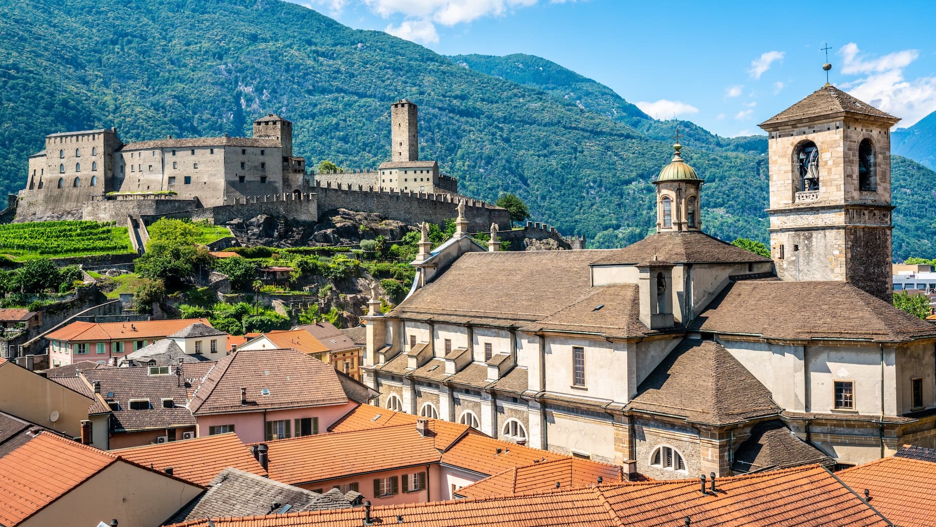Bellinzona cityscape with Castelgrande castle, Collegiata church, and green mountains, Ticino, Switzerland.