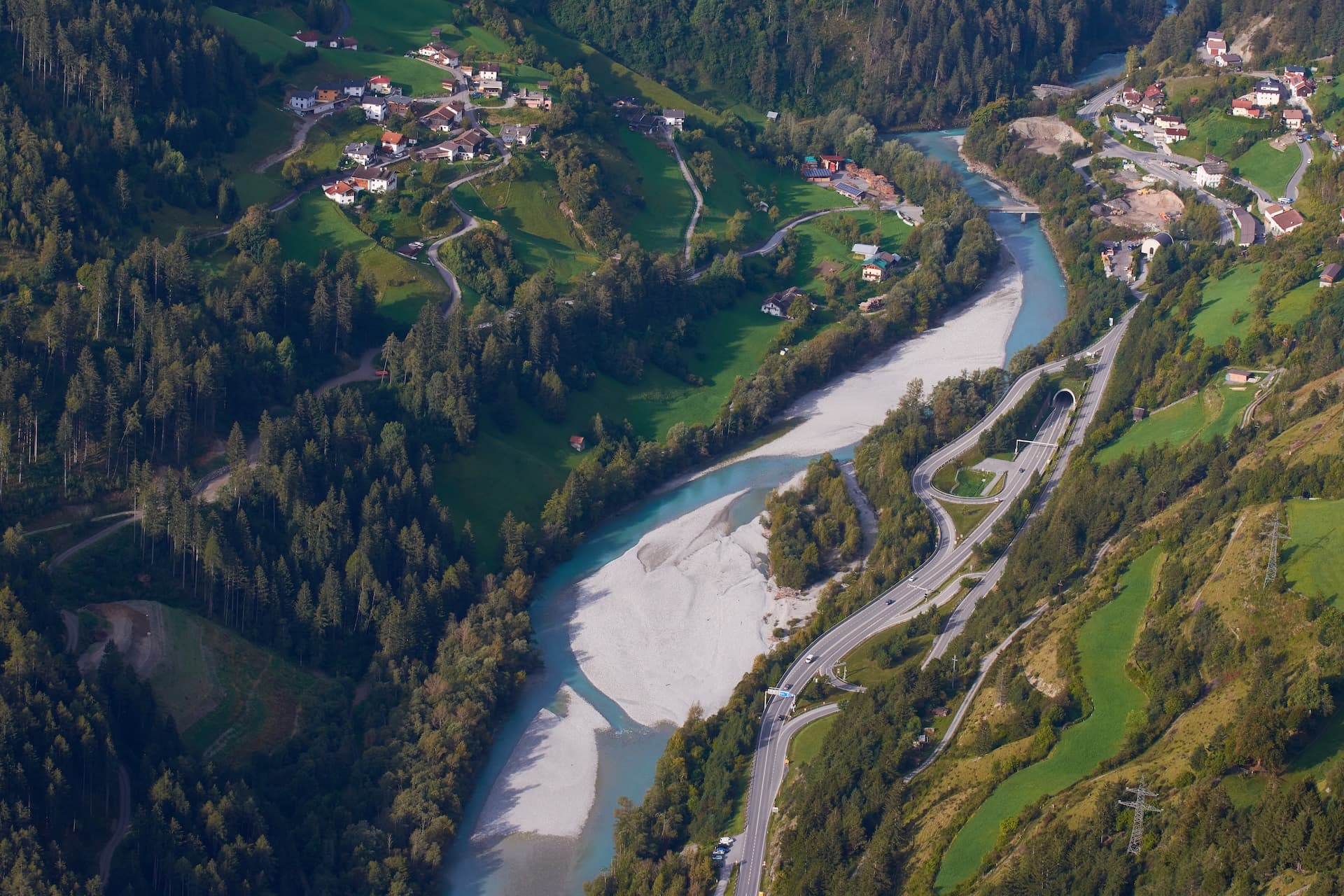 Aerial view of Inn River, wide gravel bed, and Reschenstraße highway near Prutz.