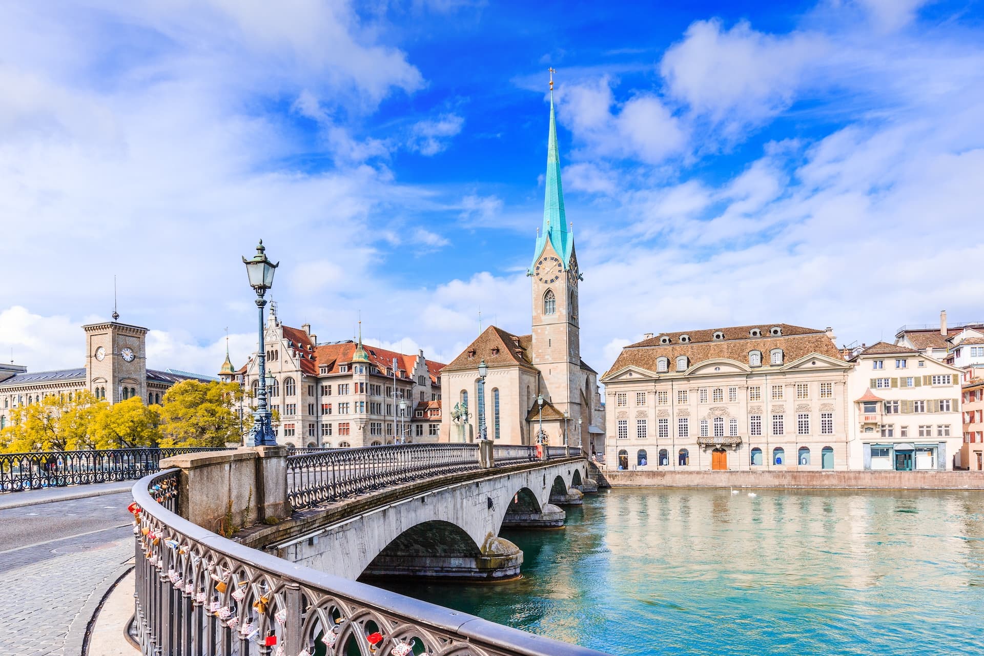 Zurich, Switzerland: Fraumunster Church, bridge, and buildings on the Limmat river under blue sky.
