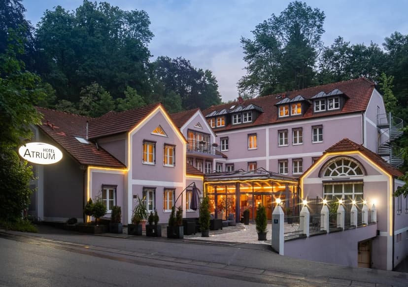 Hotel Atrium building illuminated at dusk with trees in the background, Passau.