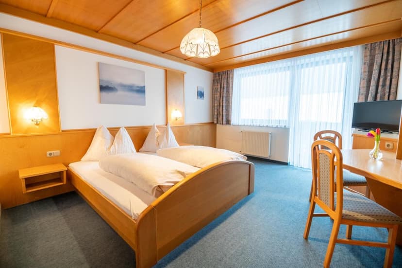 Wooden hotel room with double bed, desk, and large window in Aschach.
