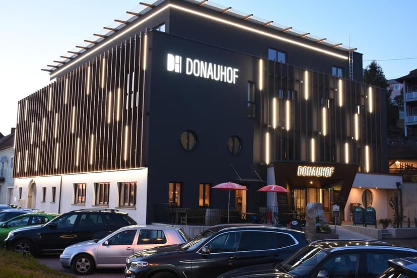 Hotel Donauhof building exterior with illuminated vertical slats and parked cars.