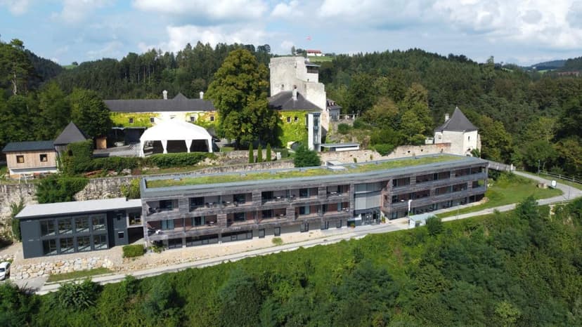 Hotel complex with modern wing and historic tower nestled in lush green hills near Marbach.
