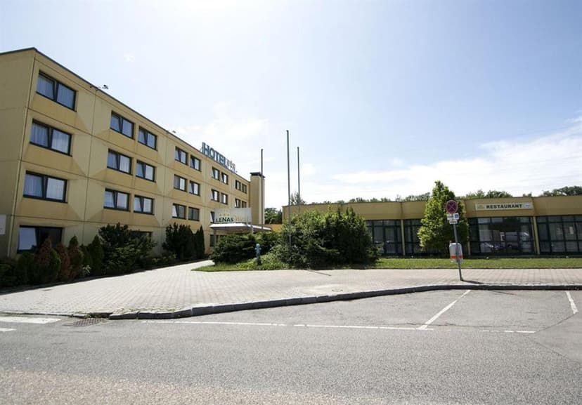 Hotel building with "LENAS West" sign and adjacent restaurant under bright sky in Tulln.