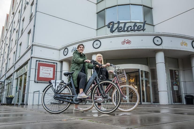 Two women with bicycles outside the Velotel building entrance.