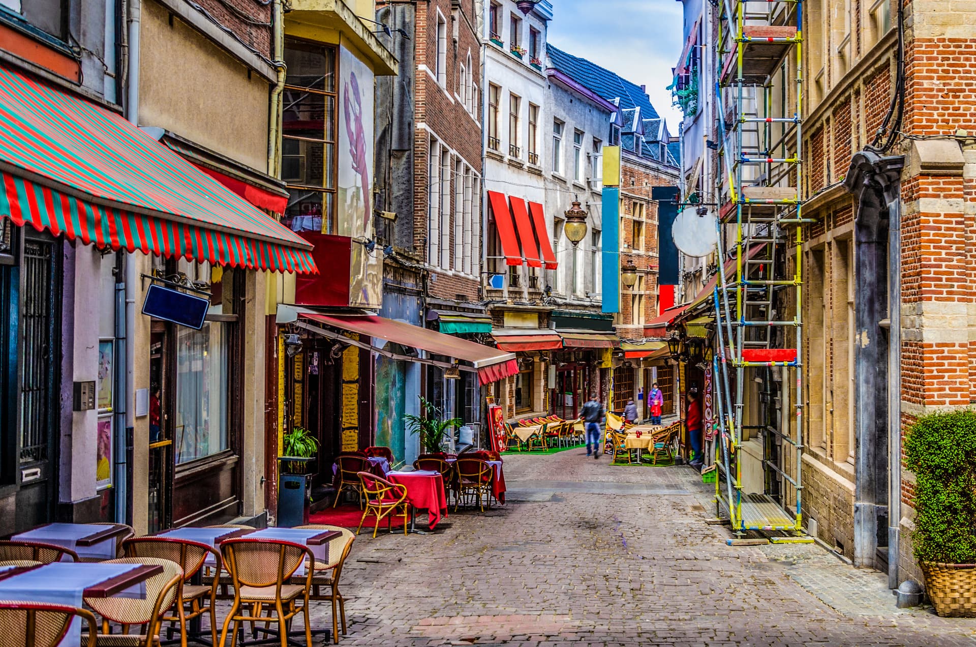 Outdoor cafe seating on a narrow cobblestone street lined with historic buildings in Brussels.
