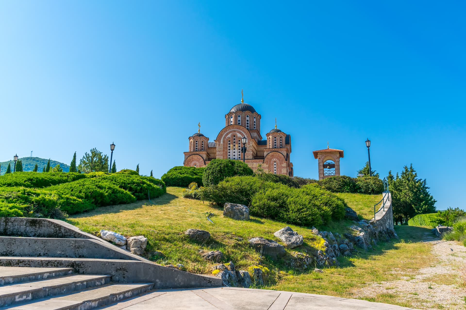Orthodox Temple in Trebinje, Bosnia and Herzegovina, on a grassy hill under a clear blue sky.