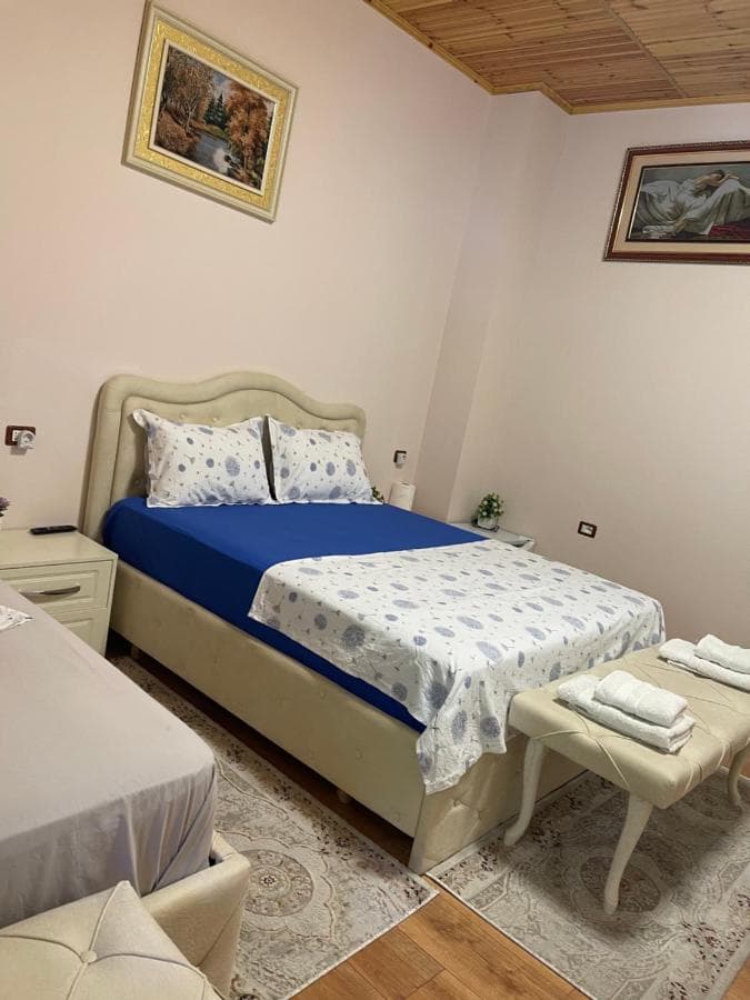 Bedroom with two beds, light pink walls, wood ceiling, and framed artwork