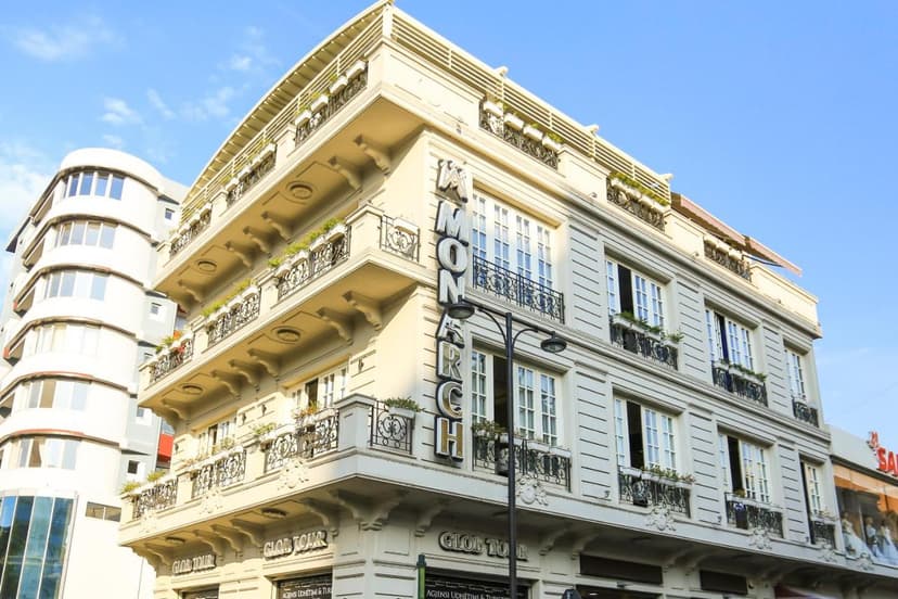 Hotel Monarch building with ornate balconies next to a modern structure under blue sky in Elbasan.