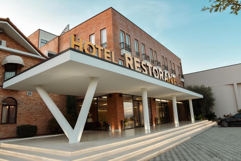 Hotel Restorant entrance with modern white canopy, brick facade, and illuminated steps at Hotel Albulena Lac