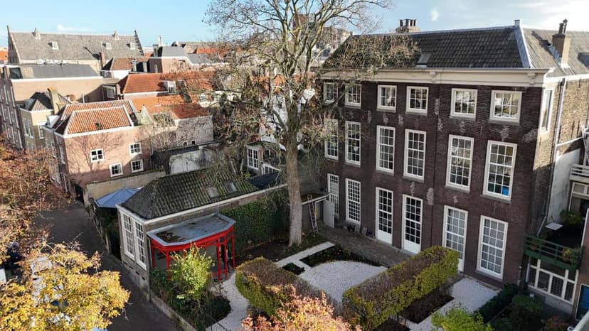 Courtyard garden with bare tree, red structure, and brick buildings in Dordrecht.