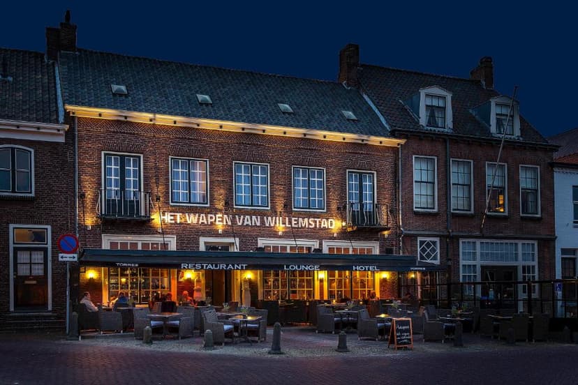 Restaurant and hotel "Het Wapen van Willemstad" illuminated at dusk with outdoor seating
