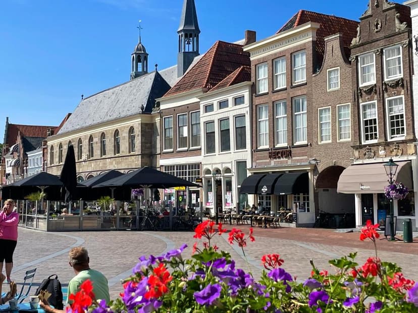 Outdoor cafe seating in Zierikzee town square with historic buildings and colorful flowers.