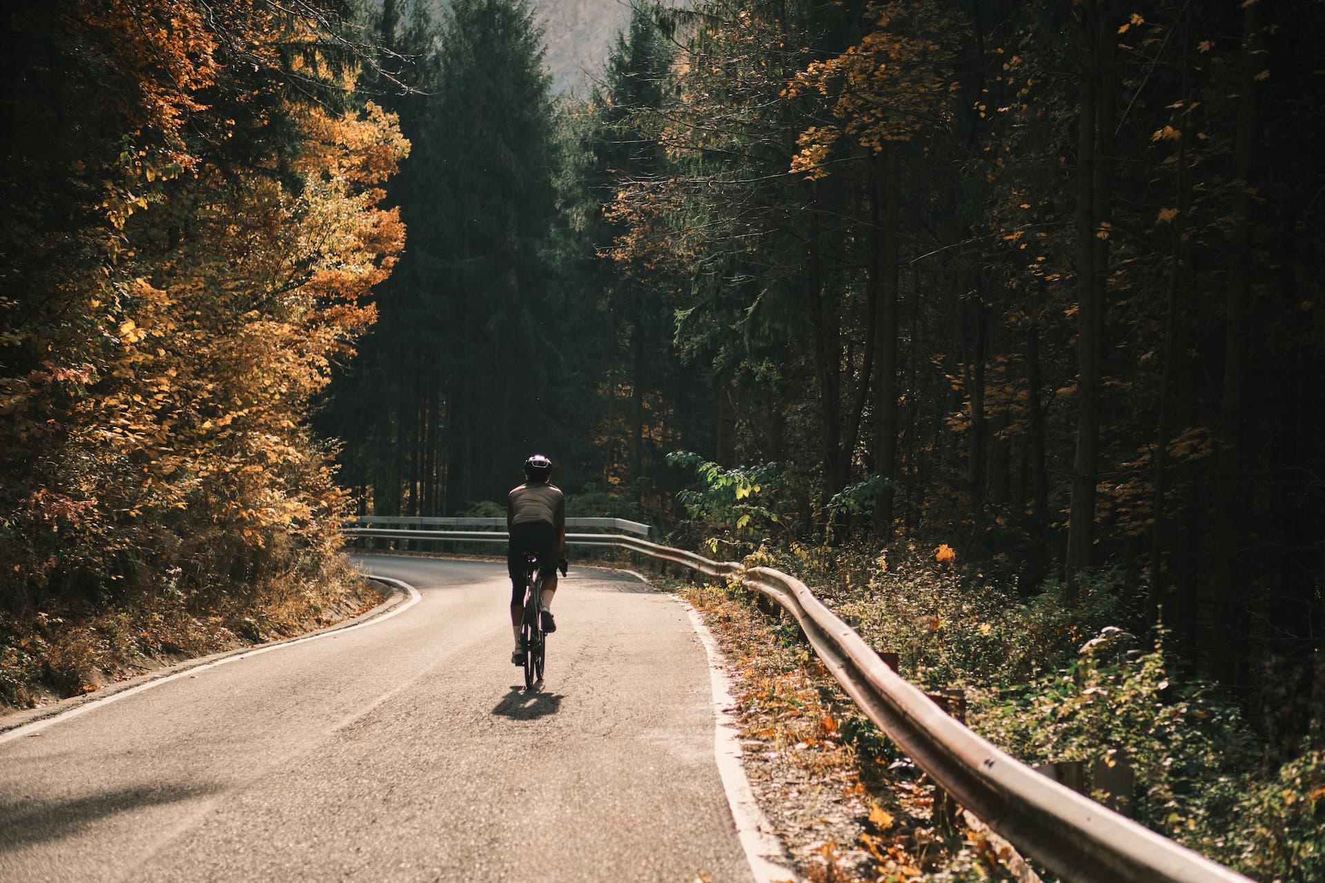 Cyclist-through-scenic-autumn-forest-road-Romania-Carpathians