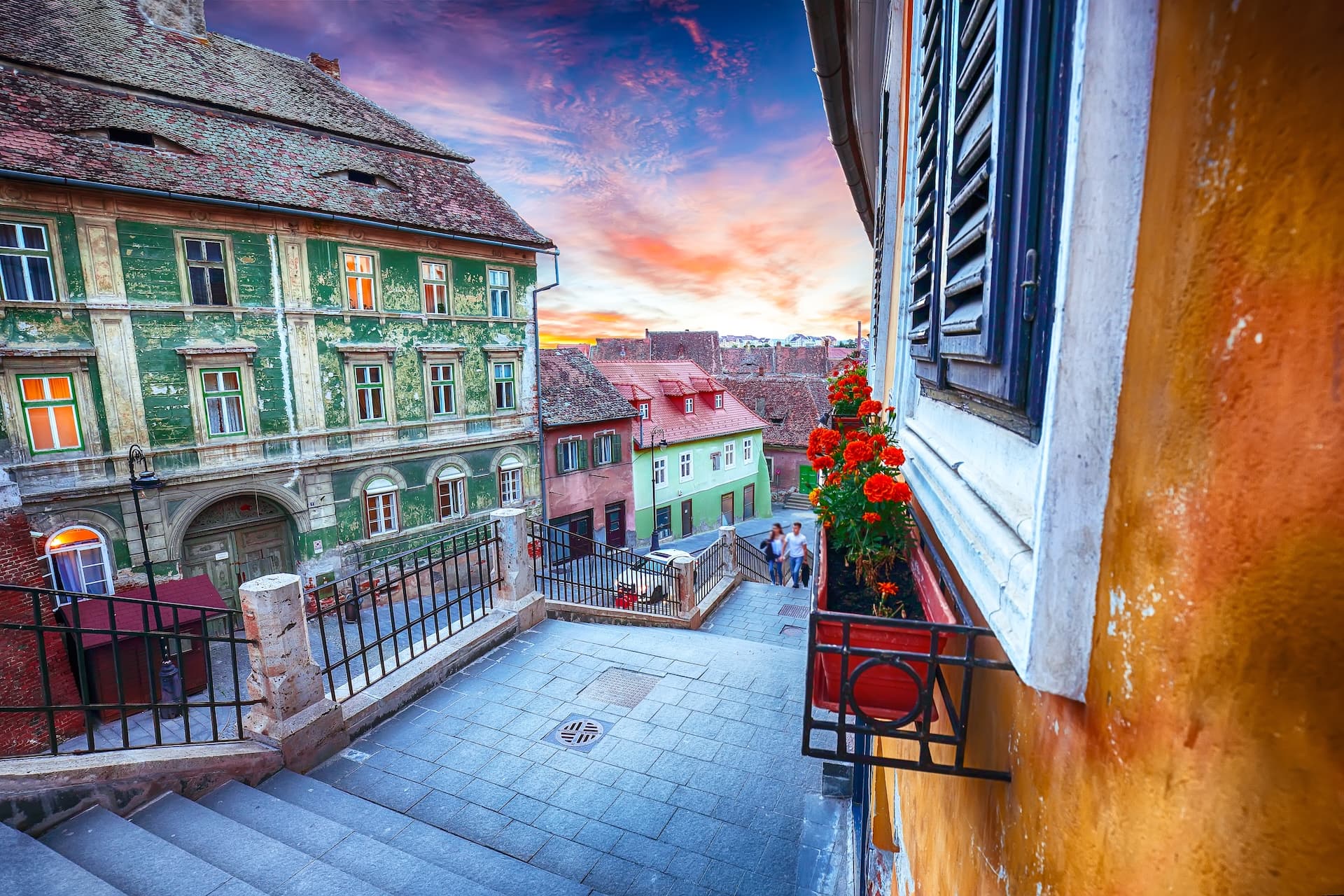 Stone steps leading down between colorful historic buildings in Sibiu, Romania at sunset.