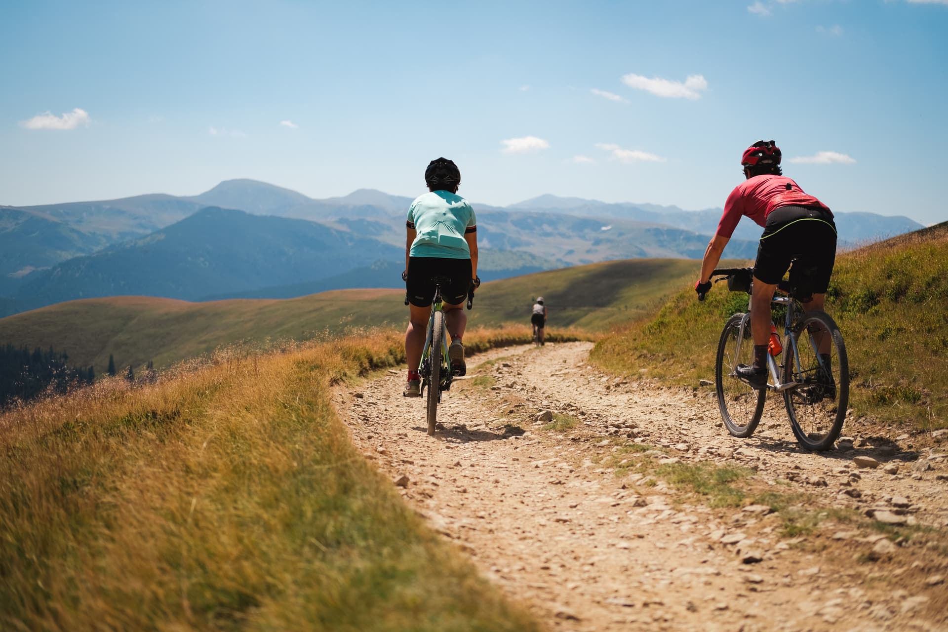 Gravel bikers on Transalpina road in Carpathian Mountains, Romania, riding on sunny day.