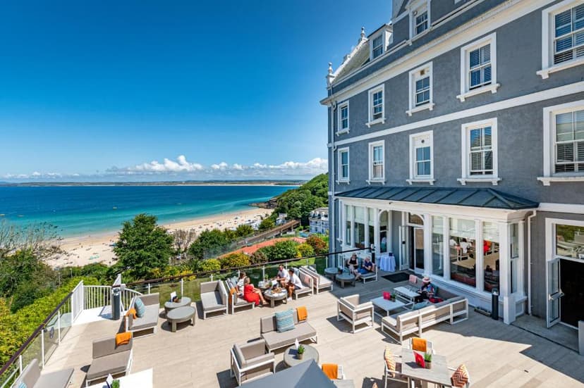 Hotel terrace dining overlooking sandy beach and turquoise ocean under clear blue sky