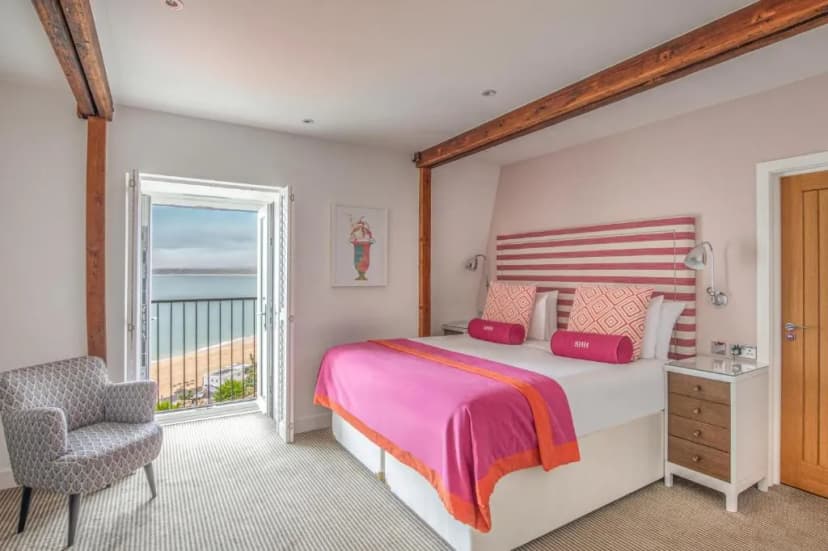 Bedroom with pink bedding and balcony view of beach and sea