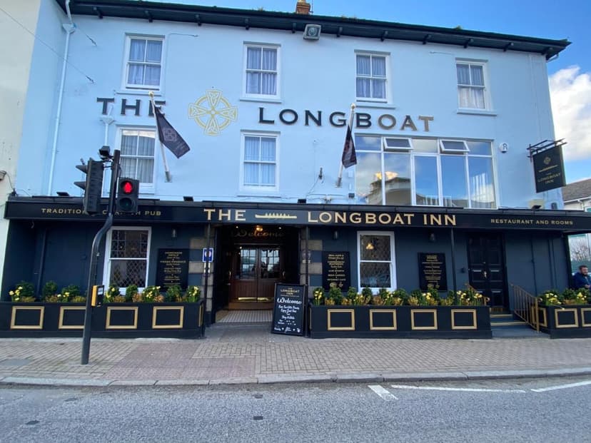 The Longboat Inn pub facade with light blue upper story and dark lower level on a street.