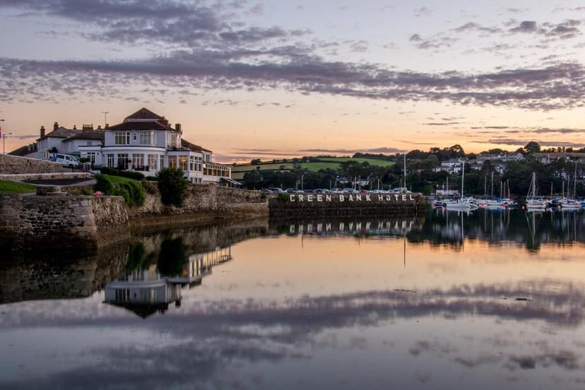Green Bank Hotel building reflected in calm water with moored sailboats at sunset
