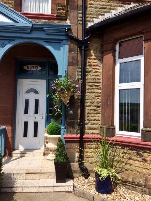 Entrance to Lismore house with white door, blue trim, and potted plants on stone steps.