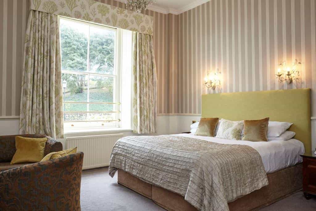 Bedroom with striped wallpaper, large window view, and bed with lime green headboard