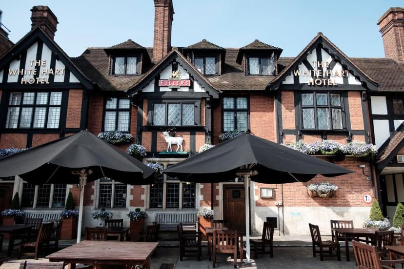 The White Hart Hotel with Tudor revival style, outdoor seating, and a white stag statue.