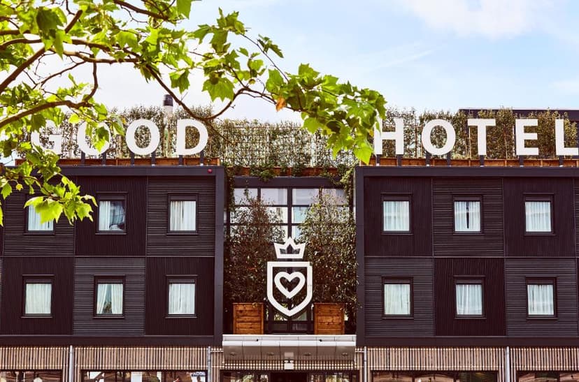Facade of Good Hotel building with large white lettering and heart logo, framed by green leaves.